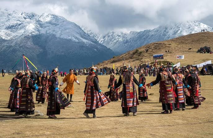 A highland community dancing on the grass below snow peaks, northern Bhutan
